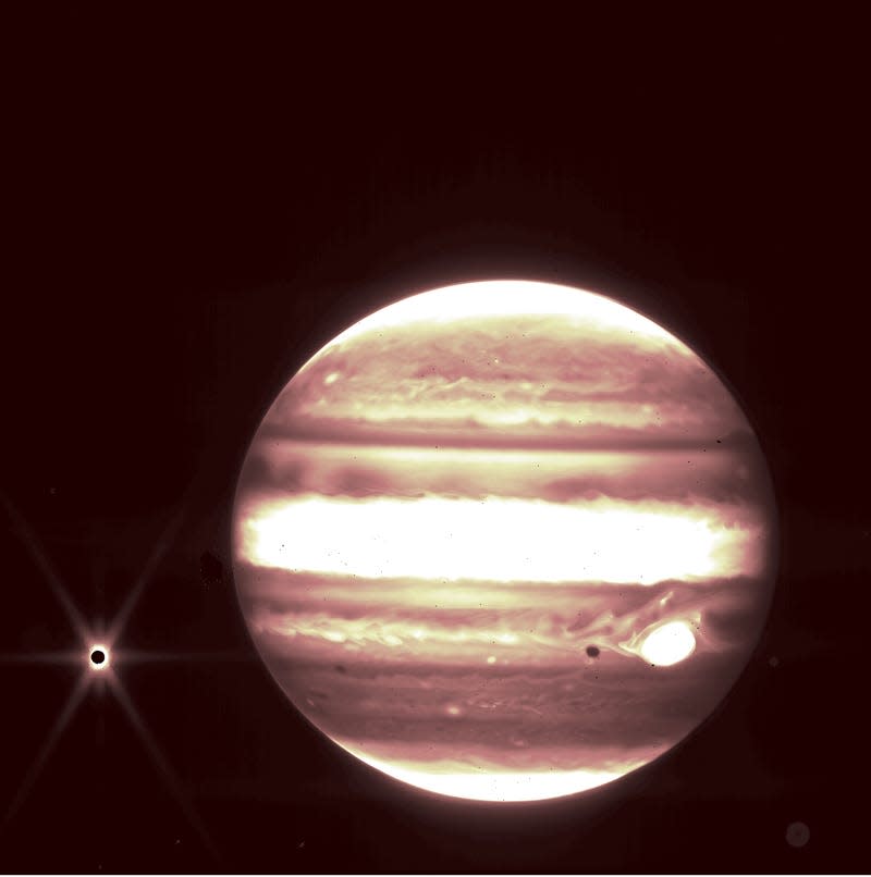 júpiter en infrarrojo blanco y naranja con luna oscura europa rodeada de luz amarilla