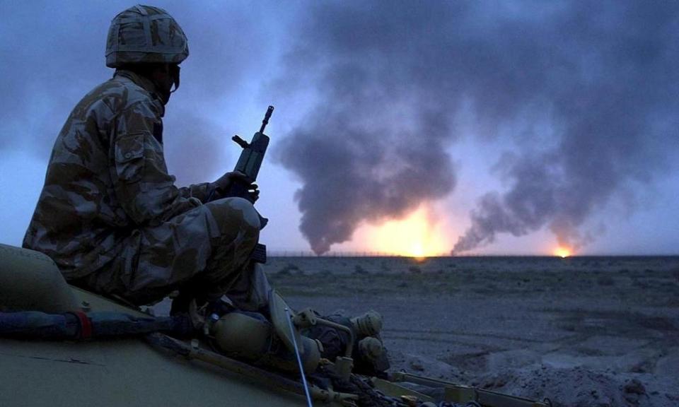 A British soldier watches oil wells burn in Southern Iraq in 2003.