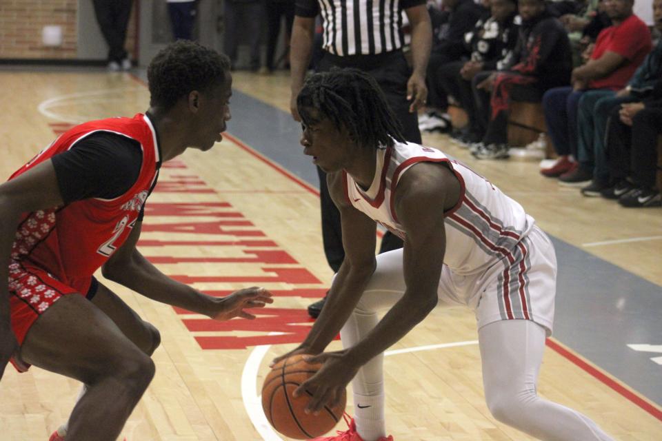 Raines guard Ta'veon Dunbar (13) dribbles as Jackson forward Ronald Durham (21) defends during the Northwest Christmas Tournament.