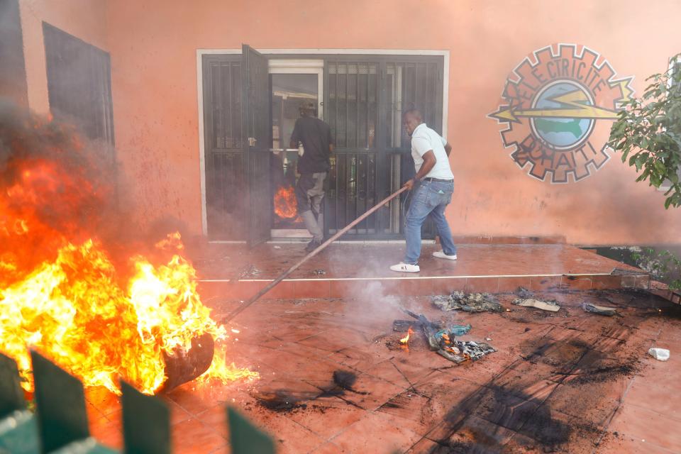 Workers put down a fire set at an office of Haiti's power company during a protest to demand the resignation of the Prime Minister Ariel Henry in Port-au-Prince, Haiti, Friday, March 1, 2024. (AP Photo/Odelyn Joseph)