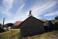 <p>Am Rande der Tour de France hat sich ein Mann mit seinem kleinen Fahrrad auf einem Dachgiebel postiert, um einen optimalen Blick auf die vorbeiradelnden Athleten zu haben. (Bild: AP Photo/Christophe Ena) </p>