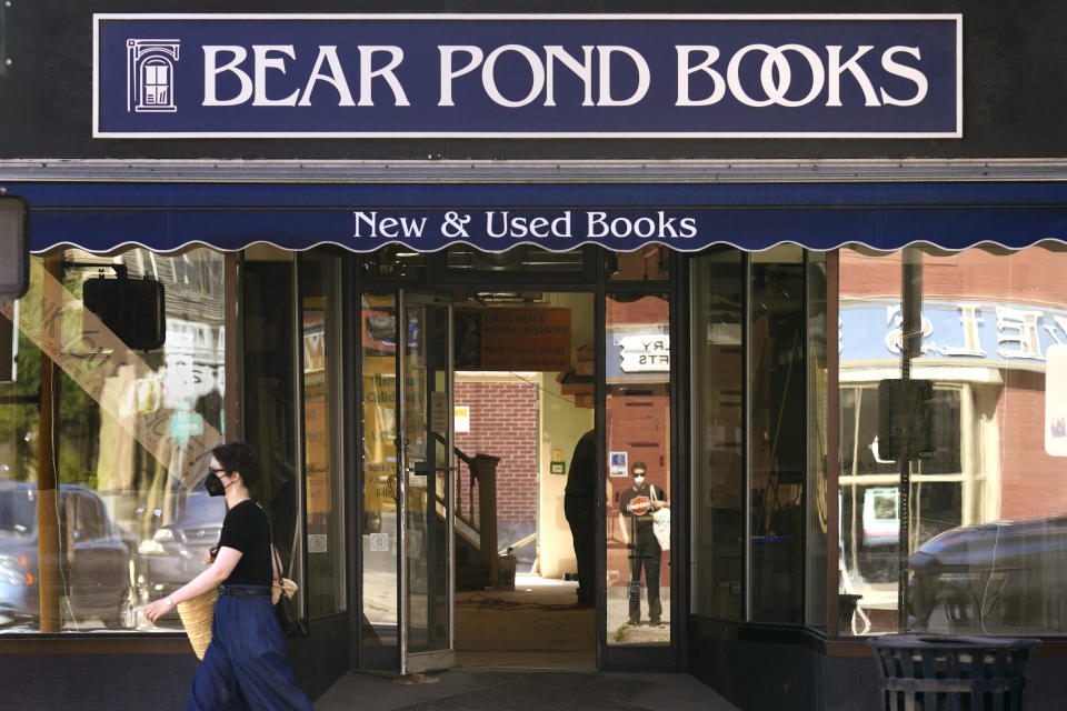 A woman, wearing a protective mask due to the airborne dust from dried floodwaters, walks past Bear Pond Books, which is rebuilding following the July floods, Tuesday, Aug. 1, 2023, in Montpelier, Vt. The mostly gutted shops, restaurants and businesses that lend downtown Montpelier its charm are considering where and how to rebuild in an era when extreme weather is occurring more often. Vermont's flooding was just one of several major flood events around the globe this summer that scientists have said are becoming more likely due to climate change. (AP Photo/Charles Krupa)