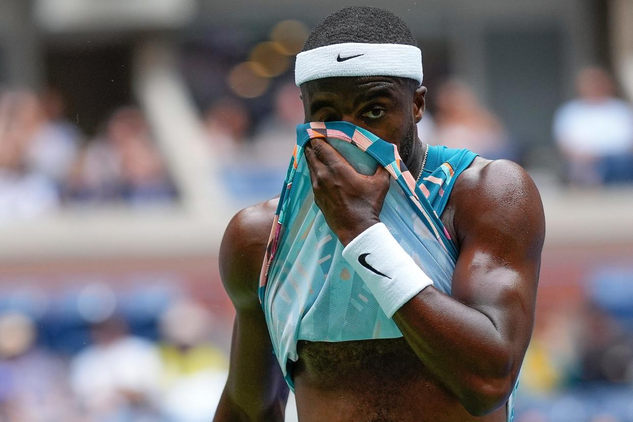 Frances Tiafoe wipes sweat off his face with his shirt.