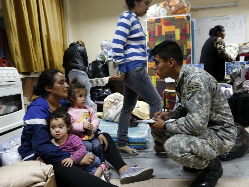 Ein Soldat der chilenischen Armee kümmert sich in einer Notunterkunft um eine Familie. Foto: Felipe Trueba