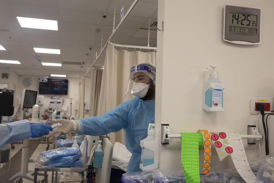 A medical professional extends his hand for fresh syringes in the coronavirus ward of the Shaare Zedek Medical Center in Jerusalem, Tuesday, Aug. 31, 2021. (AP Photo/Maya Alleruzzo)