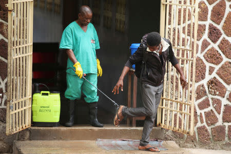 FILE PHOTO: A health worker sprays a visitor with chlorine after leaving the isolation facility, prepared to receive suspected Ebola cases, at the Mbandaka General Hospital, in Mbandaka, Democratic Republic of Congo May 20, 2018. REUTERS/Kenny Katombe/File Photo