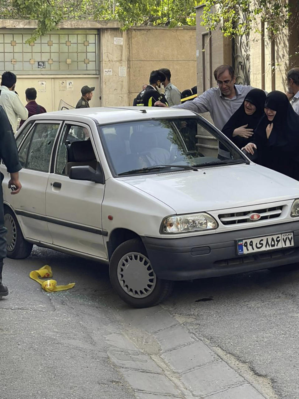 In this photo provided by Islamic Republic News Agency, IRNA, family members of Col. Hassan Sayyad Khodaei weep over his body at his car after being shot by two assailants in Tehran, Iran, Sunday, May 22, 2022. Hassan Sayyad Khodaei, a senior member of Iran's powerful Revolutionary Guard, was killed outside his home in Tehran on Sunday by unidentified gunmen on a motorbike, state TV reported. (IRNA via AP)