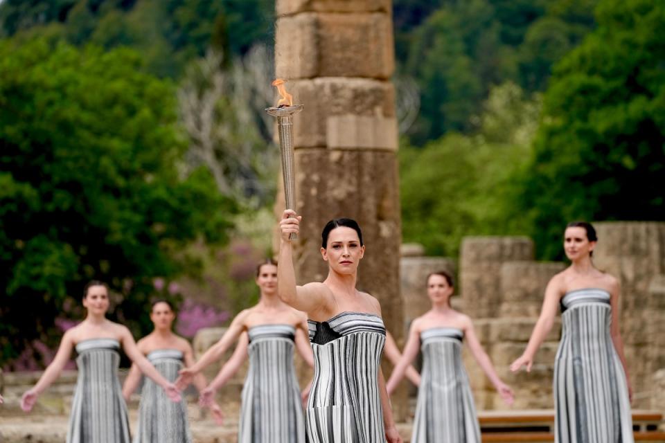 扮演古希臘女祭司的演員瑪麗米娜（Mary Mina）點燃銀火炬。（圖：IOC media）