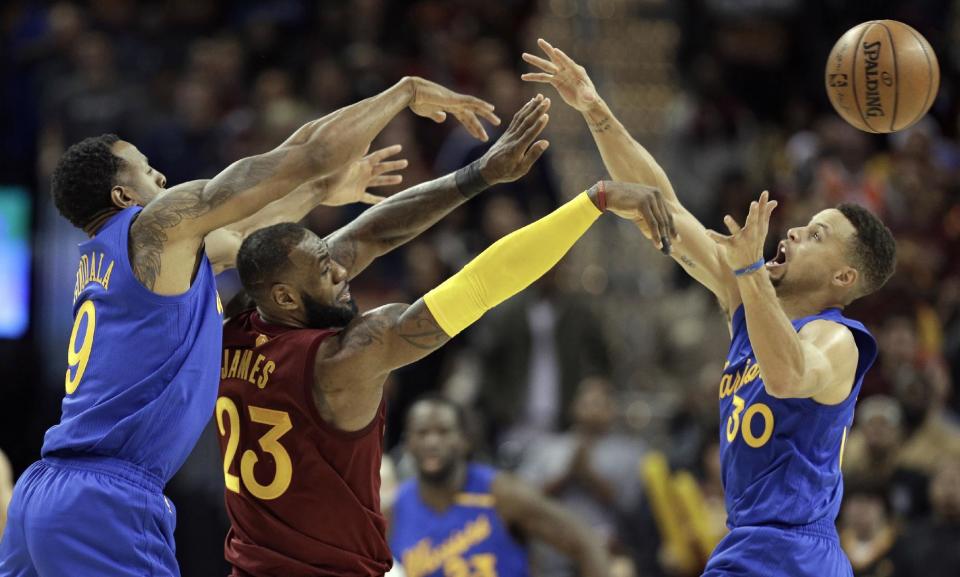 Cleveland Cavaliers' LeBron James (23) passes over Golden State Warriors' Stephen Curry (30) as Andre Iguodala (9) defends in the second half of an NBA basketball game, Sunday, Dec. 25, 2016, in Cleveland. The Cavaliers won 109-108. (AP Photo/Tony Dejak)