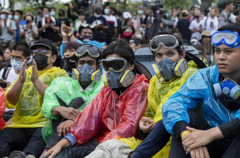 Pro-democracy protesters wearing protective masks sometimes used to avoid tear gas sit on the road during a march near Sanam Luang in Bangkok, Thailand, Sunday, Sept. 20, 2020. The mass student-led rally that began Saturday is the largest in a series of protests this year, with thousands camping overnight near the royal palace, demanding for new elections and reform of the monarchy. (AP Photo/Gemunu Amarasinghe)