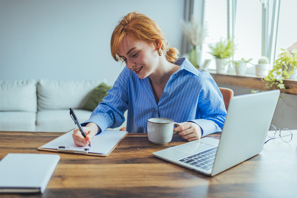 Smiling beauyiful girl preparing school homework, using laptop, happy black schoolgirl, pupil doing tasks, writing essay, studying at home, making notes, writing, reading textbooks