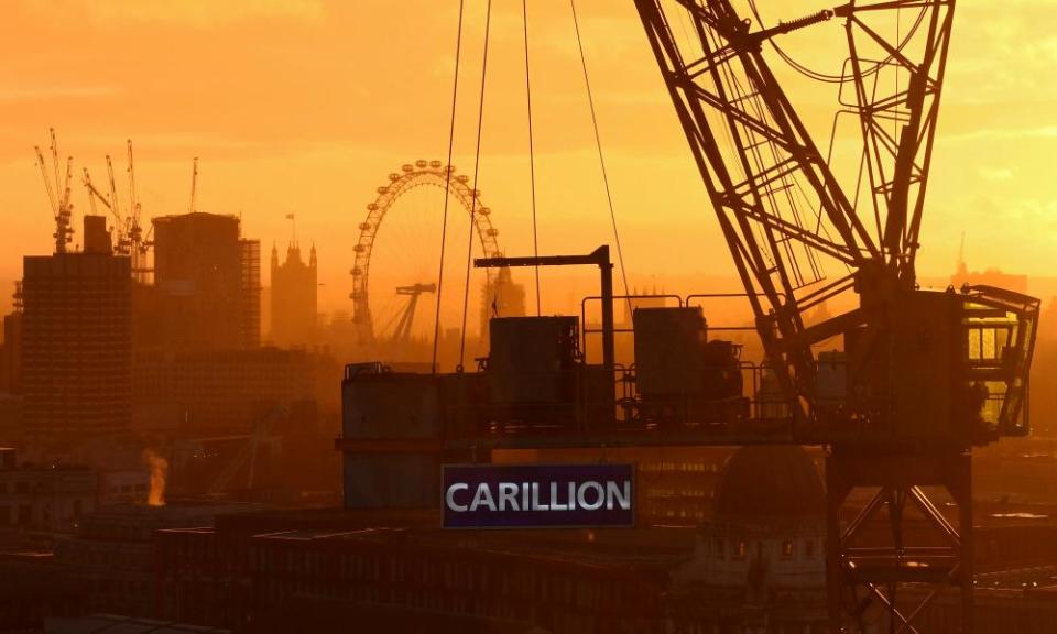 The sun sets behind a construction crane showing the branding of British construction company Carillion photographed on a building site in central London