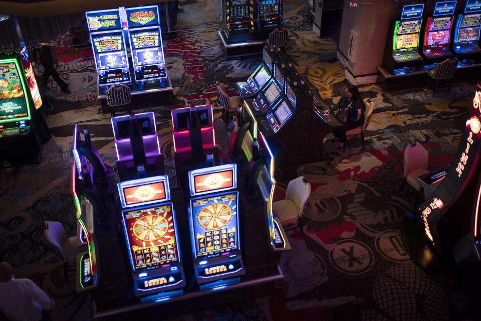 A woman sits at a slot machine in a casino in Las Vegas, Sunday, Nov. 8, 2020. Las Vegas sells itself on fantasies of wealth, luxury, and sex, and even the most cynical first-time visitor can come here expecting at least a hint of James Bond playing baccarat in Monte Carlo. That would be a mistake. (AP Photo/Wong Maye-E)