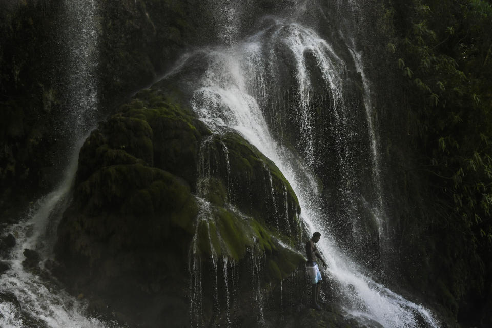 A voodoo pilgrim bathes in a waterfall believed to have purifying powers during an annual celebration in Saut d' Eau, Haiti, on July 16, 2021. (AP Photo/Matias Delacroix)