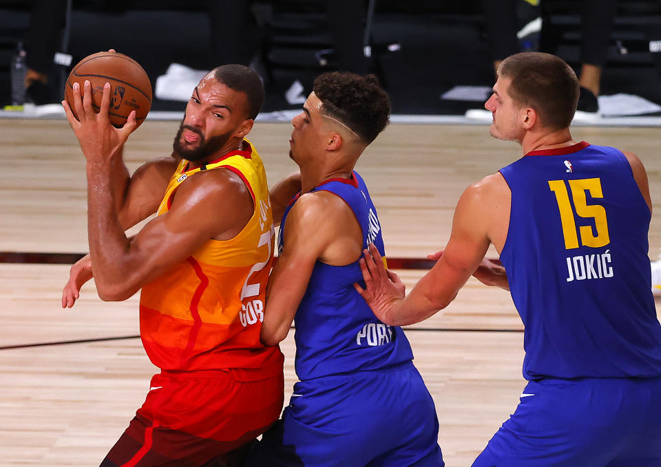 Utah Jazz's Rudy Gobert, left, is defended by Denver Nuggets' Michael Porter Jr., center, and Nikola Jokic (15) during the third quarter of an NBA basketball game Saturday, Aug. 8, 2020, in Lake Buena Vista, Fla. (Kevin C. Cox/Pool Photo via AP)