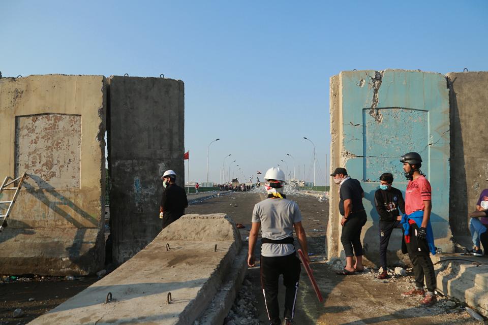Anti-government protesters pull down concrete walls on Al-Sanak Bridge leading to the Green Zone during a demonstration in Baghdad, Iraq, Thursday, Oct. 31, 2019. Late Wednesday, hundreds of people headed to the Al-Sanak Bridge that runs parallel to the Joumhouriya Bridge, opening a new front in their attempts to cross the Tigris River to the Green Zone. Security forces fired volleys of tear gas that billowed smoke and covered the night sky. (AP Photo/Hadi Mizban)