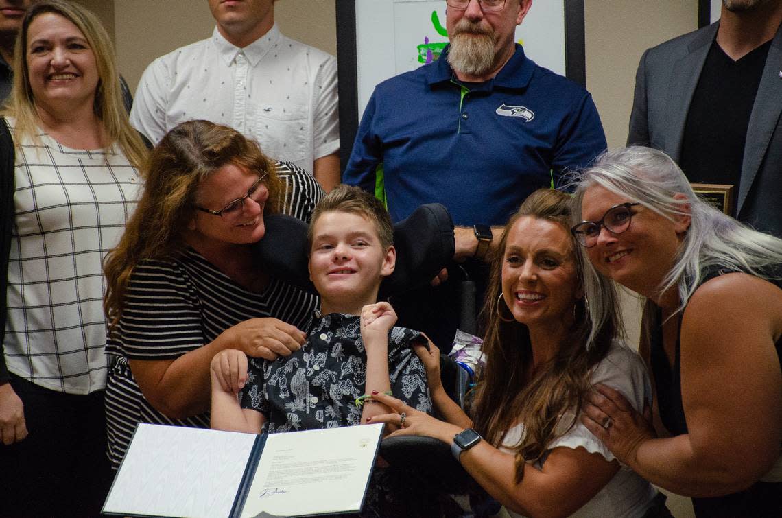 Gabe Scheel, a special education student at Ray Reynolds Middle School, smiles for the camera alongside teachers and his family at a Pasco School Board meeting. The 13-year-old uses eye-gaze technology to learn and paint artwork, which was recognized by Washington Gov. Jay Inslee.