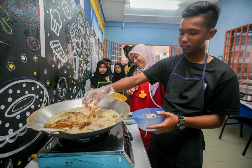 A student of SMK Sentosa frying mushrooms cultivated by the school’s special needs students. — Picture by Farhan Najib