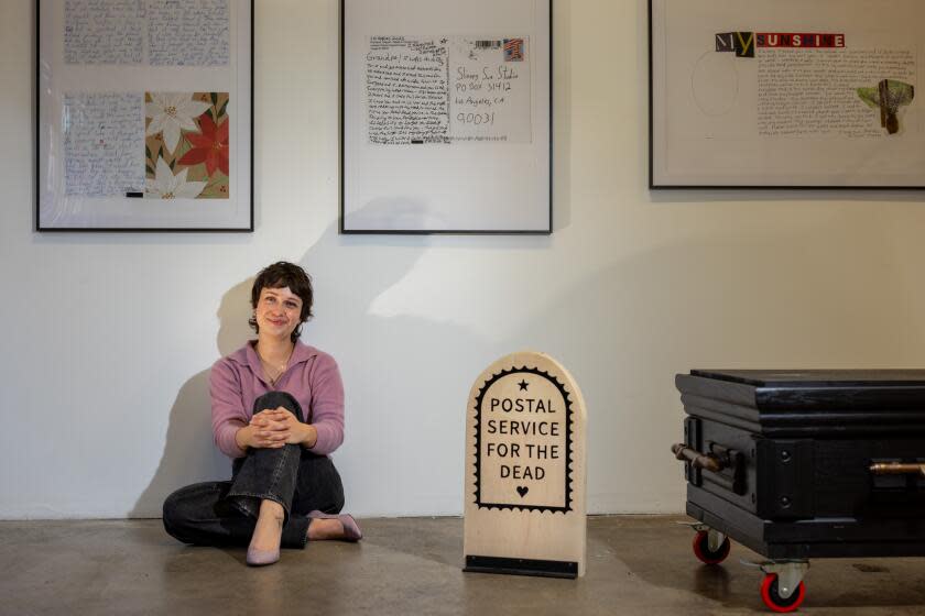 Los Angeles, CA - December 05: Artist Janelle Ketcher, who runs a service called Postal Service for the Dead, where she maintains a P.O. Box where people can send letters to their deceased loved ones, is photographed in the middle of an exhibit of some of the letters, at Studio Death Doula LA, in downtown Los Angeles, CA, Tuesday, Dec. 5, 2023. Ketcher receives letters from people and with symbols drawn on the envelope (a heart, a star, or nothing), she knows if she should open it, but keep it private, open it and can make it public, or not open at all, respectively. (Jay L. Clendenin / Los Angeles Times)