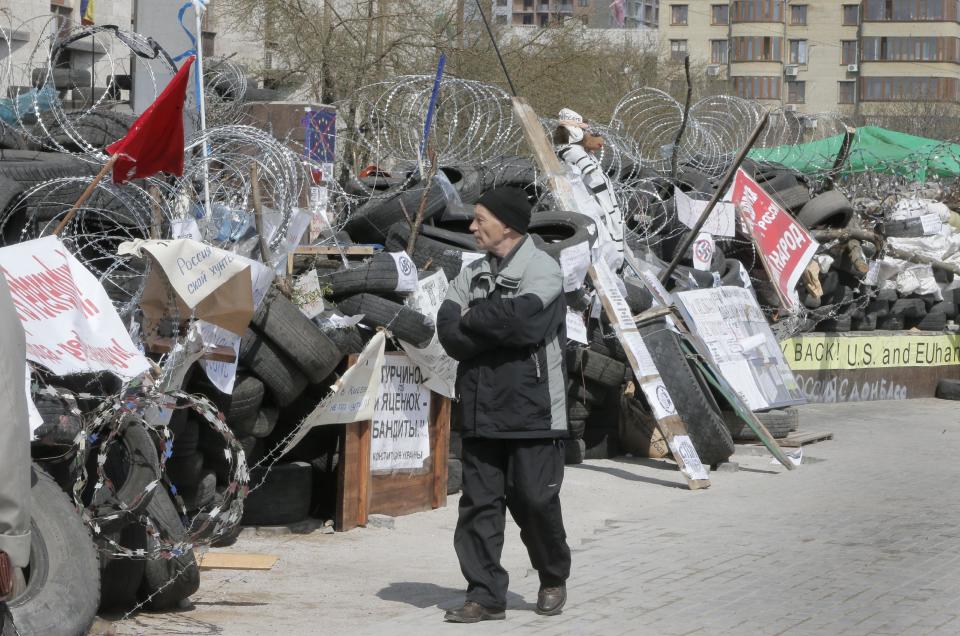 A man passes by the pro-Russian activist barricades at a regional administration building that they had seized earlier in Donetsk, Ukraine, Tuesday, April 15, 2014. Several government buildings have fallen to mobs of Moscow loyalists in recent days as unrest spreads across the east of the country. (AP Photo/Efrem Lukatsky)