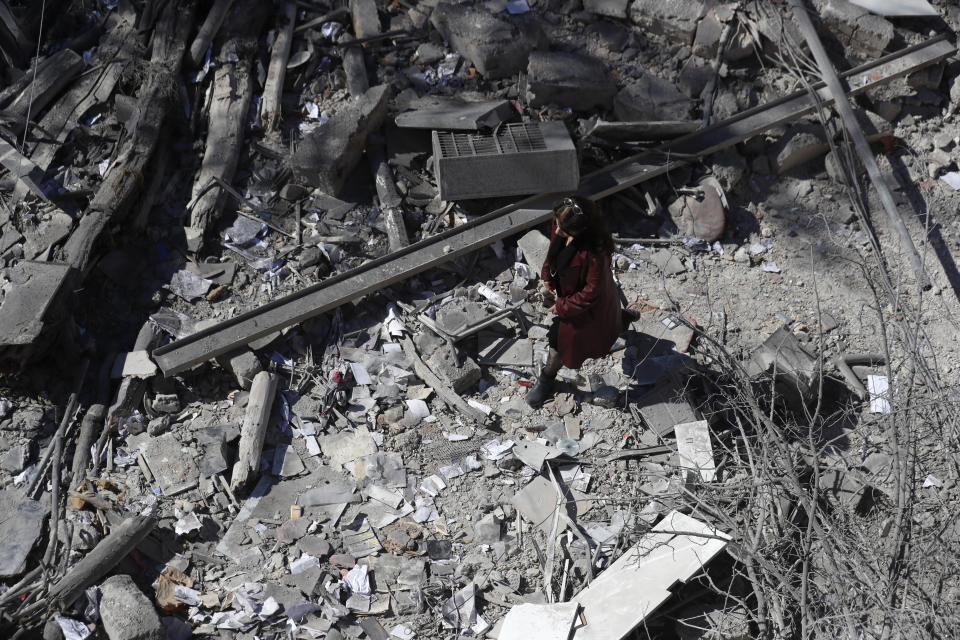 A woman inspects the damage of a medieval citadel and an applied arts institute house after an early morning Israeli airstrike in the capital city of Damascus, Syria, Sunday, Feb. 19, 2023. Syrian state news reported that Israeli airstrikes have targeted a residential neighborhood in central Damascus. (AP Photo/Omar Sanadiki)