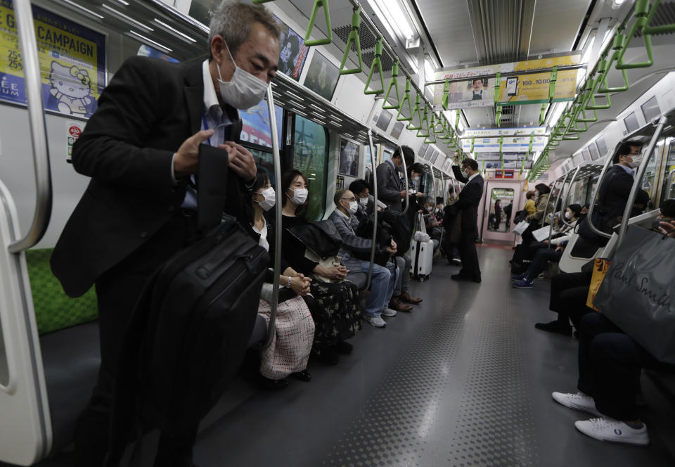 A man wearing a face mask gets off train in Tokyo on Thursday, Nov. 19, 2020. Japan's number of reported coronavirus infections hit a record high Thursday, and the prime minister urged maximum caution but stopped short of calling for restrictions on travel or business. (AP Photo/Hiro Komae)