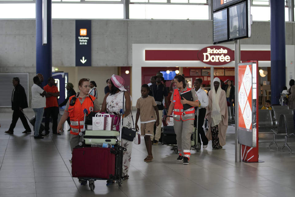 Worker of Red Cross take care of people evacuated from Niger at the Roissy Charles de Gaulle airport, north of Paris, France, Wednesday, Aug. 2, 2023. European militaries are continuing to evacuate foreign nationals from Niger, with a third French military flight expected to depart the African nation's capital. Defense chiefs from West Africa's regional bloc are set to meet to discuss last week's coup against the country's democratically elected president. (AP Photo/Christophe Ena)