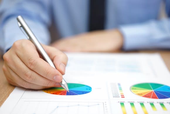 A man points to a pie chart with a pen.