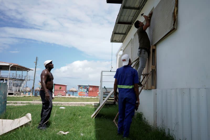 Workers protect the windows of a bar in anticipation of the Tropical Storm Laura arrival, in Havana