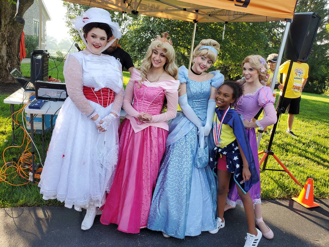 Mary Poppins, Aurora, Cinderella and Rapunzel cosplayers pose with a CASA Superhero Run participant. Many cosplayers, including Disney princesses and superheroes, will be on hand at Saturday’s race at WinStar Farm.