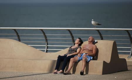 A couple sunbathe on the promenade on a hot Summer day in Blackpool, Britain July 1, 2015. REUTERS/Phil Noble