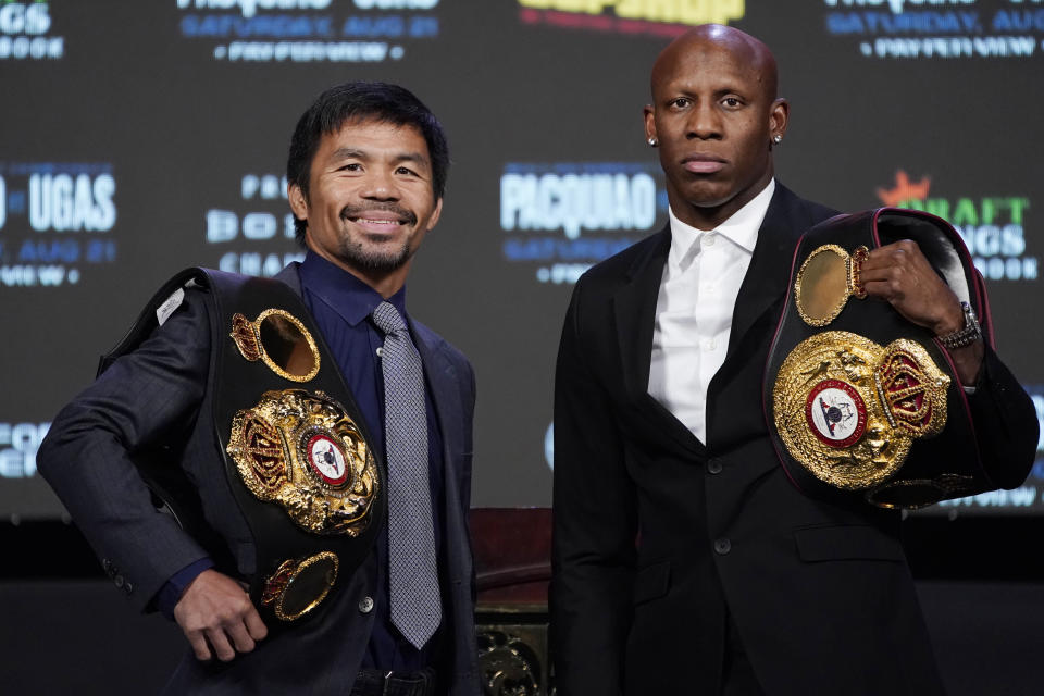 Manny Pacquiao, left, of the Philippines, and Yordenis Ugas, of Cuba, pose for photographers during a news conference Wednesday, Aug. 18, 2021, in Las Vegas. The two are scheduled to fight in a welterweight championship bout Saturday in Las Vegas. (AP Photo/John Locher)