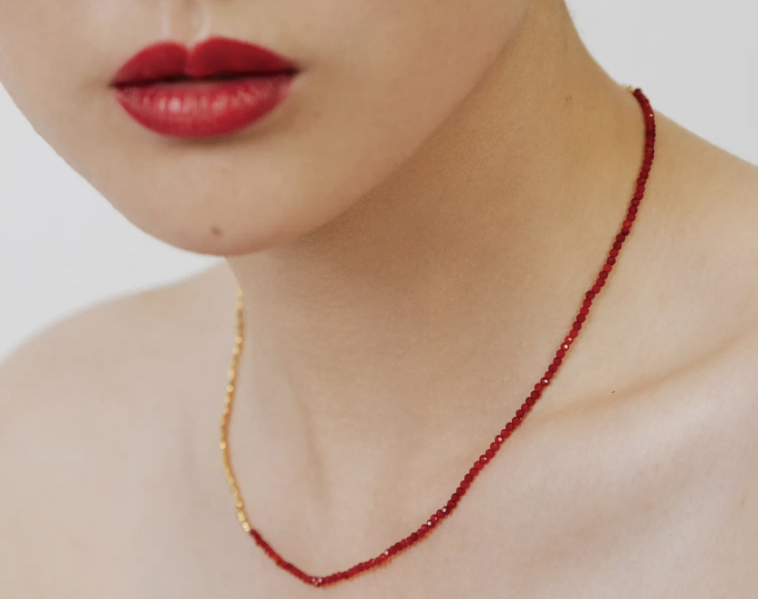 model with red lipstick wearing gold and red Monica Vinader Mini Nugget Stone Beaded Necklace (Photo via Nordstrom)