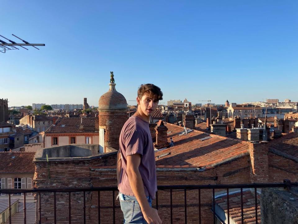 A boy standing on a balcony that overlooks Toulouse