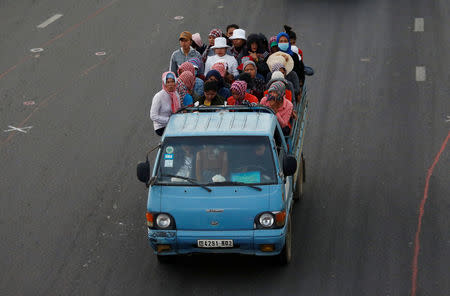 Garment workers stand on the back of a truck as they travel to work, on the outskirts of Phnom Penh, Cambodia, October 17, 2018. REUTERS/Samrang Pring