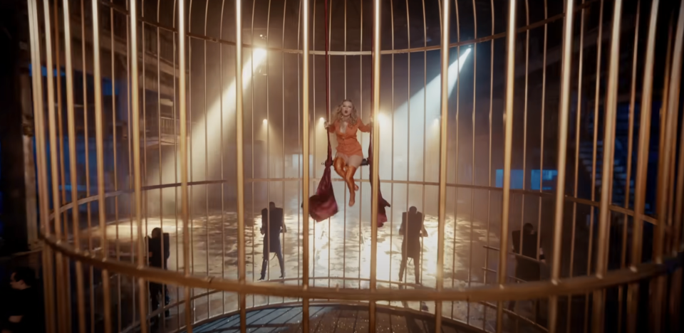 Taylor in an elegant dress seated inside a large birdcage