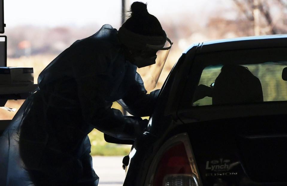 A registered nurse from TestIowa reaches into a car to take a nasopharyngeal swab from a patient at a drive-thru coronavirus testing station at Iowa State University Research Park on Nov. 13, 2020, in Ames, Iowa.