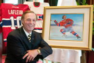 Former hockey star Guy Lafleur poses next to one of 10 paintings of moments from his career by artist Mario Beaudoin, Tuesday, May 18, 2004, in Montreal. Montreal Canadiens legend Guy Lafleur has died at age 70. (Paul Chiasson/The Canadian Press via AP)