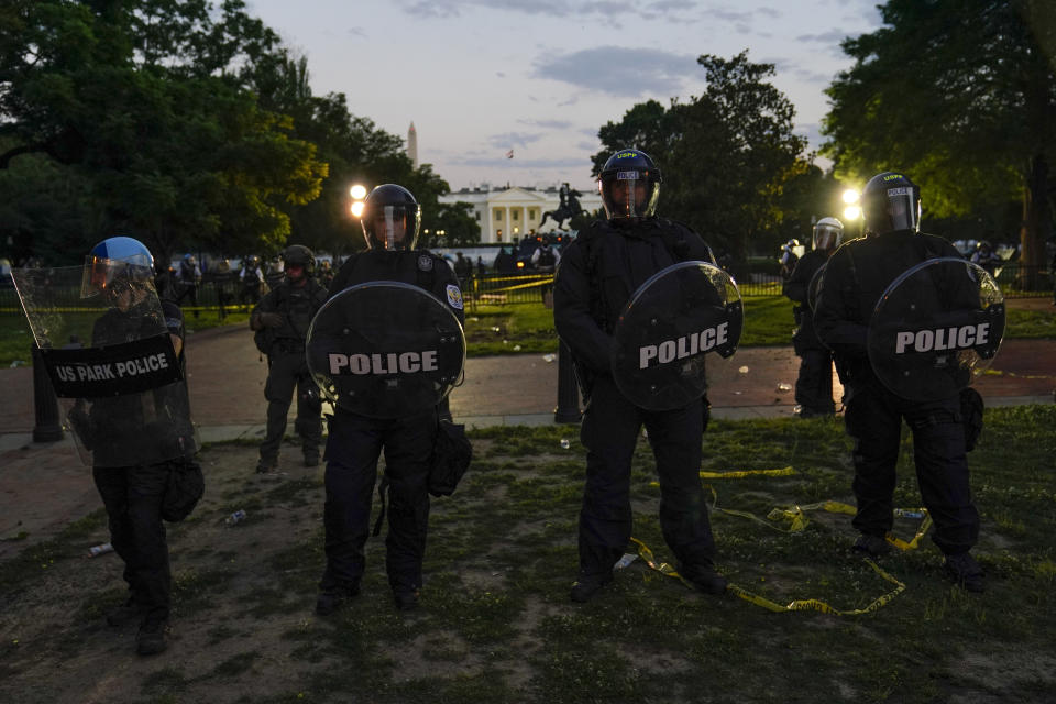 FILE - In this May 30, 2020, file photo, police in riot gear stand in front of the White House as demonstrators gather to protest the death of George Floyd, outside the White House in Washington. Still reeling from the coronavirus pandemic and street protests over the police killing of Floyd, exhausted cities around the nation are facing yet another challenge: A surge in recent shootings has left dozens dead, including young children. (AP Photo/Evan Vucci, File)