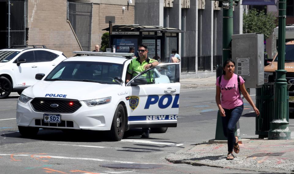 A police officer stands near a road work project in downtown New Rochelle June 14, 2022. Some municipal workers throughout the region will receive hazard pay bonuses for working through the first year of COVID, with payments as high as $3,000 for first responders and essential workers in New Rochelle, and up to $5,000 for most city of Mount Vernon employees.