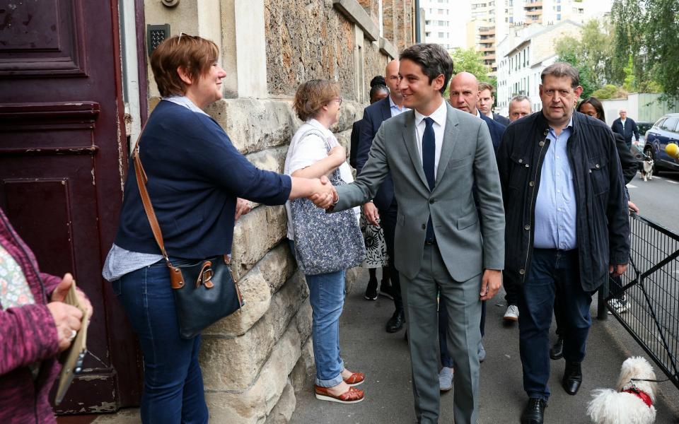 France's Prime Minister Gabriel Attal (C) shakes hands with a woman upon his arrival to vote in the second round of France's parliamentary elections at a polling station in Vanves, suburb of Paris on July 7, 2024. France votes in legislative elections on July 7, 2024 that will be decisive in determining its political future and could see the far right become the largest party in parliament for the first time. (Photo by Alain JOCARD / AFP) (Photo by ALAIN JOCARD/AFP via Getty Images)