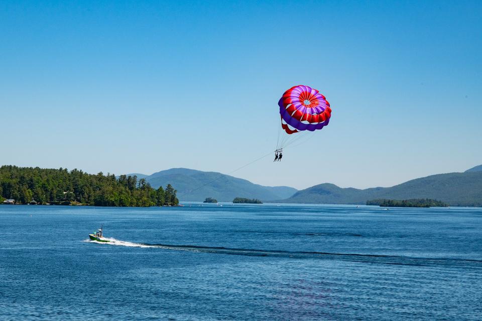 View of Lake George and mountains with two parasailing persons in the foreground.