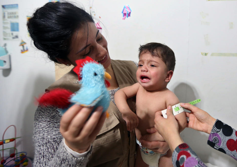 In this Tuesday, March. 11, 2014 photo, aid workers measure the upper arm circumference, to check for signs of malnutrition in one year-old Syrian refugee Mahmoud al-Khatar at a medical clinic in the town of Kab Elias in Lebanon's Bekaa Valley. Three years after Syria’s uprising began to overthrow President Bashar Assad, spiraling into a war that has killed over 140,000 people and sending over 2.5 million people fleeing into neighboring countries, aid workers say are now seeing malnutrition emerge, once a barely known scourge in Syrian society. (AP Photo/Bilal Hussein)