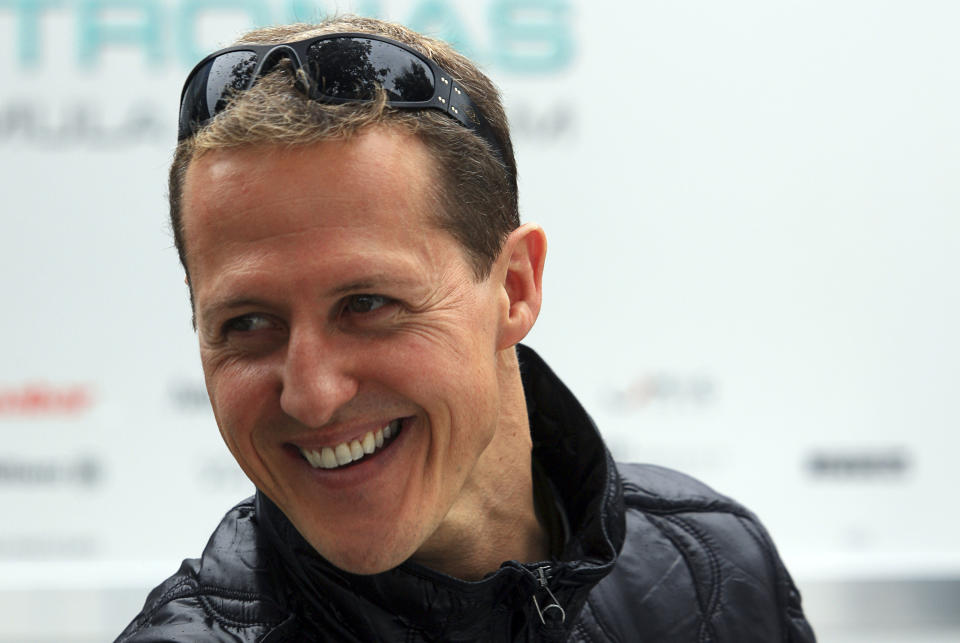 Mercedes Formula One driver Michael Schumacher of Germany smiles at the back of the pits ahead of this weekend's Australian Grand Prix in Melbourne March 24, 2011. The Australian F1 race, to be held on March 27, is the first race of the season after the event was cancelled in Bahrain due to political unrest.  REUTERS/Scott Wensley (AUSTRALIA - Tags: SPORT MOTOR RACING)