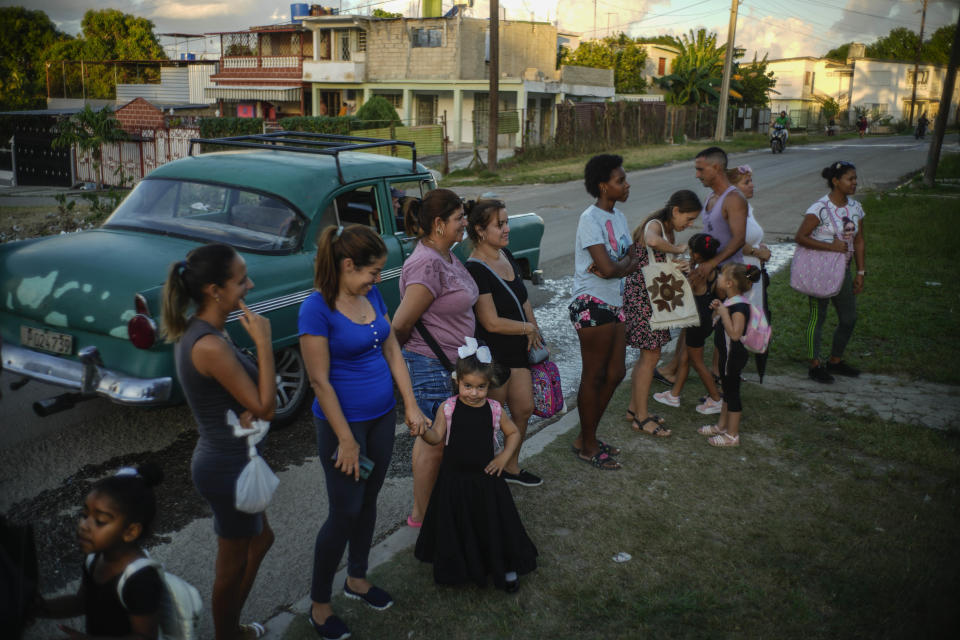 La estudiante de danza Aliss Capiro Crúz, en el centro, junto a su madre y a otros padres esperando que sus hijos salgan de una clase de baile organizada por el proyecto comunitario Espejo en el municipio de San Miguel del Padrón en las afueras de La Habana, Cuba, el martes 24 de octubre de 2023. Los padres pagan a los profesores una matrícula de 700 pesos cubanos (29 dólares al tipo de cambio oficial) al mes, una suma elevada para las familias más humildes. (Foto AP/Ramón Espinosa)