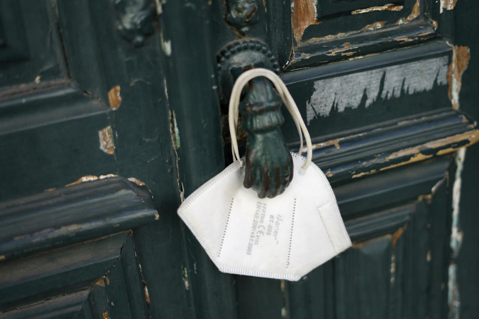 A face mask hangs from a door knocker in Lisbon, Saturday, Sept. 25, 2021. Portugal is scrapping many of its remaining COVID-19 restrictions, after becoming the world leader in the vaccination rollout, but the wearing of face masks will still be mandatory on public transport, in hospitals and care homes, and in shopping malls. (AP Photo/Armando Franca)