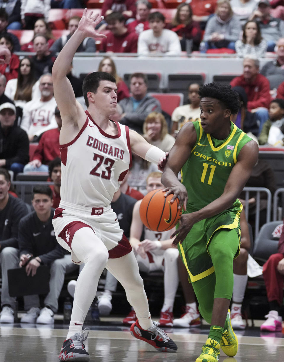 Oregon forward Mookie Cook (11) passes the ball around Washington State forward Andrej Jakimovski (23) during the first half of an NCAA college basketball game Saturday, Jan. 6, 2024, in Pullman, Wash. (AP Photo/Ted S. Warren)