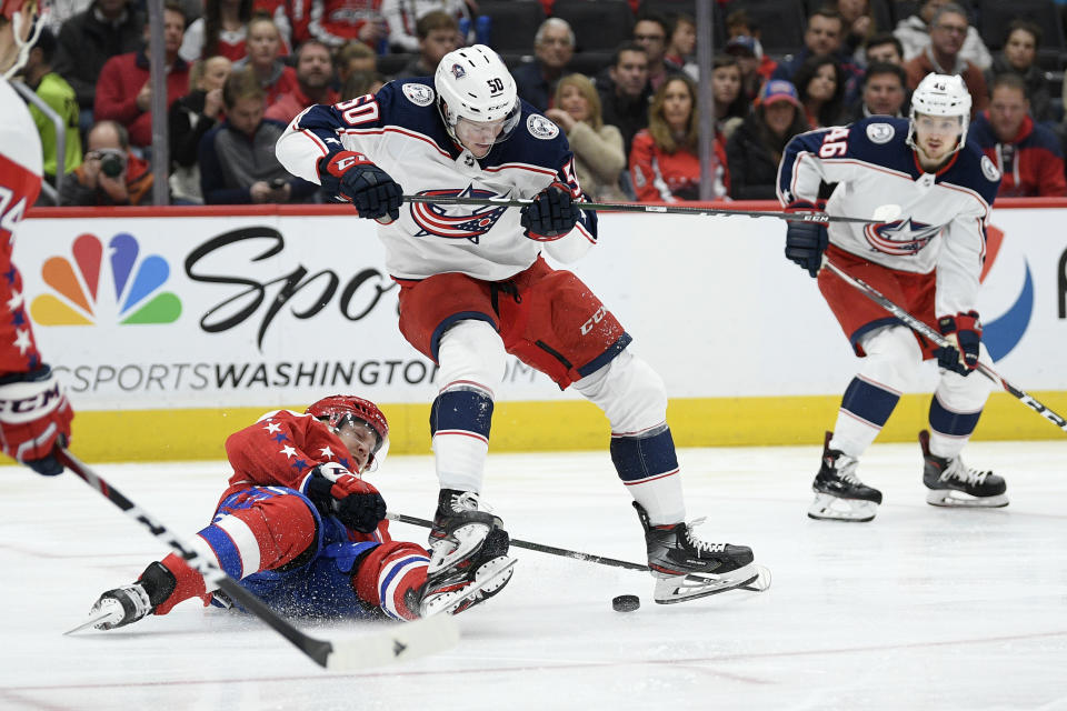 Washington Capitals center Lars Eller, bottom, and Columbus Blue Jackets left wing Eric Robinson (50) compete for the puck during the first period of an NHL hockey game Friday, Dec. 27, 2019, in Washington. (AP Photo/Nick Wass)