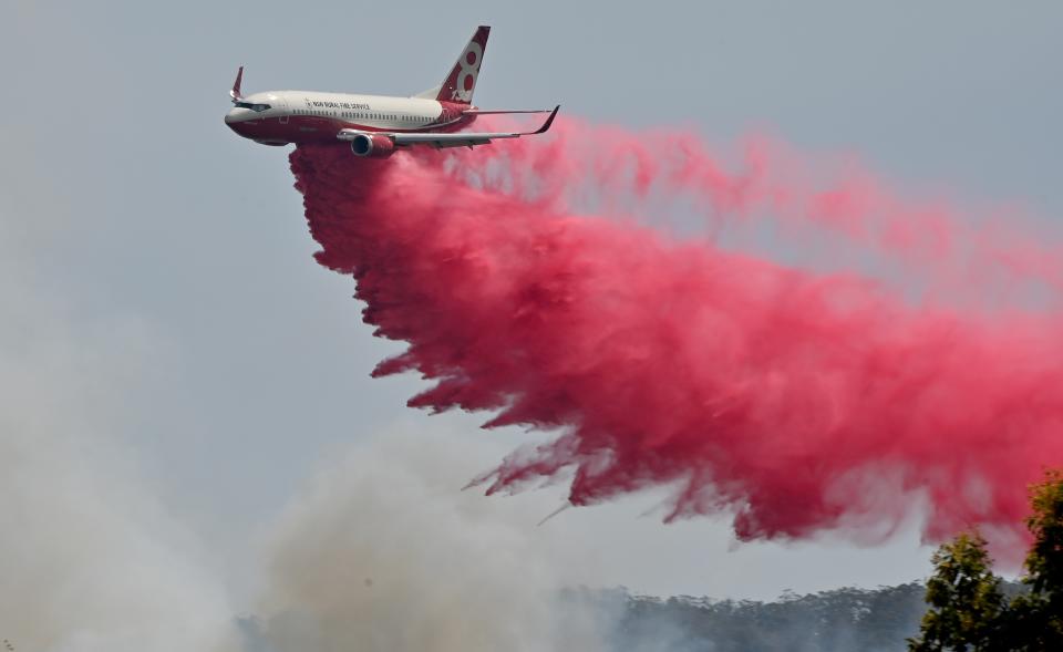 TOPSHOT - A Rural NSW Fire Service plane drops fire retardent on an out of control bushfire near Taree, 350km north of Sydney on November 12, 2019. - A state of emergency was declared on November 11, 2019 and residents in the Sydney area were warned of "catastrophic" fire danger as Australia prepared for a fresh wave of deadly bushfires that have ravaged the drought-stricken east of the country. (Photo by PETER PARKS / AFP) (Photo by PETER PARKS/AFP via Getty Images)