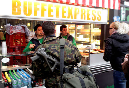 A Swiss soldier carries his assault rifle as he stands in front of a food kiosk at the central railway station after returning from manoeuvres in Zurich, Switzerland April 5, 2013. REUTERS/Arnd Wiegmann/File Photos